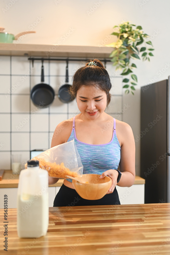 Portrait of young fitness woman in sportswear preparing breakfast on kitchen counter Portrait of young fitness woman in sportswear preparing breakfast on kitchen counter