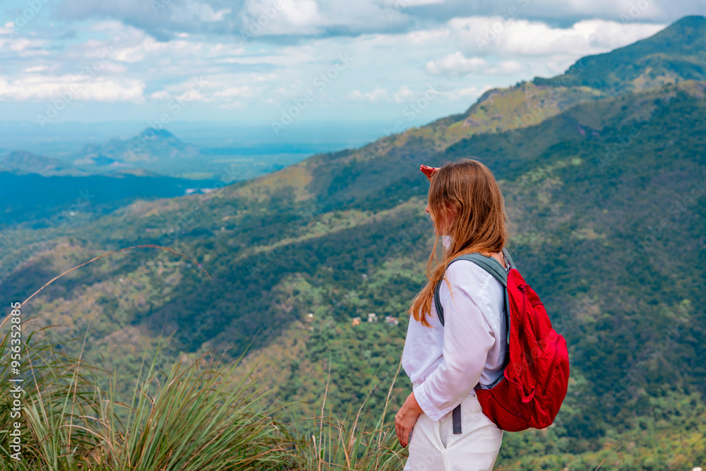 Naklejka premium middle-aged woman with a backpack went hiking and admires picturesque and epic View from the Small Adam Peak Mountain in Sri Lanka
