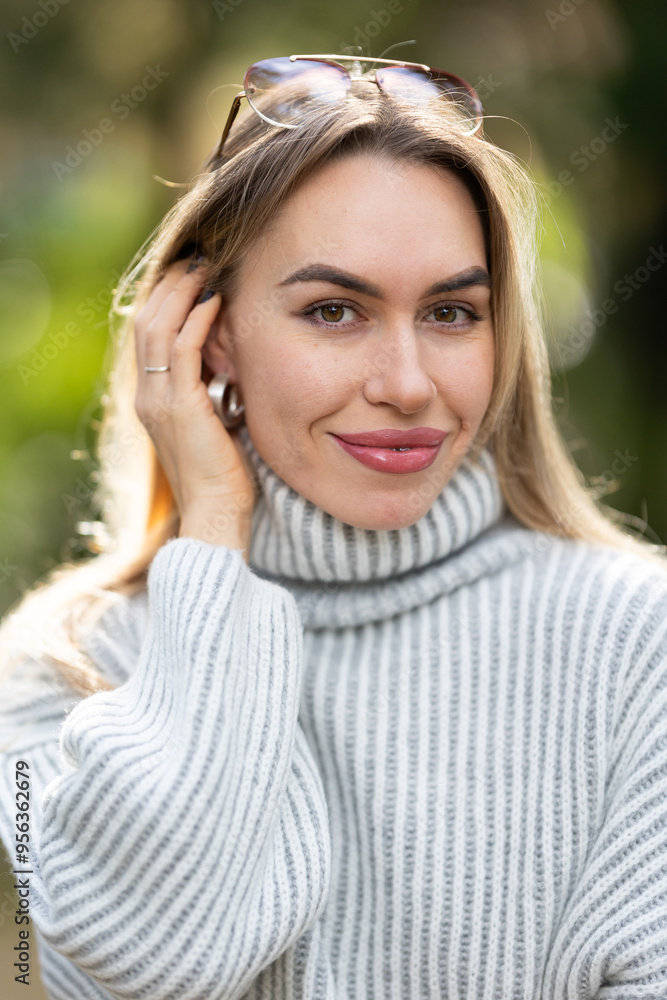 Attractive young woman smiling and touching her hair in a park Attractive young woman smiling and touching her hair in a park