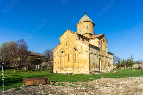 Ertatsminda St. Estate church. Graveyard, green grass. Old rusted iron gate. Bright blue sky