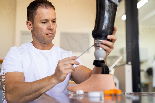 Technician adjusting prosthetic leg in lab, focusing on precise alignment