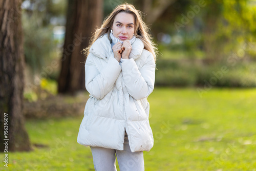 Young woman feeling cold wearing white winter coat outdoors