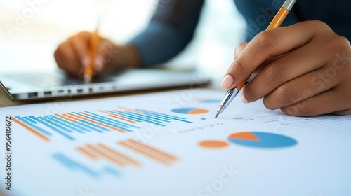 Close-up of hands writing on a business plan with a laptop in the background, startup strategy