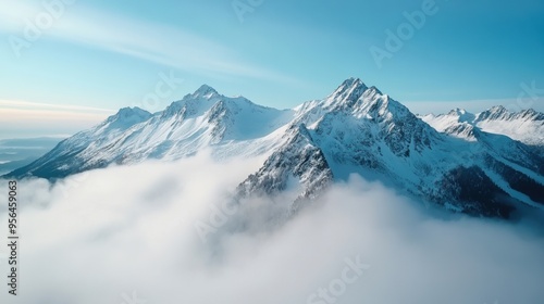 Aerial a rugged mountain range with snow-capped peaks and mist rising from the valleys below, a dramatic and awe-inspiring scene