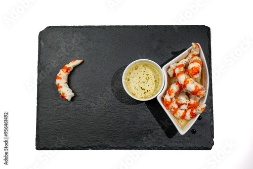 A plate of food with white sauce and surimi in the form of shrimp. On a plate of food there is a shrimp tail. Surimi in the form of shrimp on a white background. photo