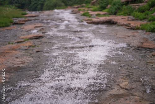 Serene River Flowing Through Rocky Terrain, Scenic Landscape with a Cascading Waterfall, Natural Beauty Lush Greenery and Rushing Water Stock Photo.