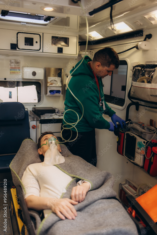 paramedic healthcare emergency staff taking care of a lying down young woman patient on stretcher with medical ventilator system and bag-valve masks inside an medical service ambulance car. paramedic healthcare emergency staff taking care of a lying down young woman patient on stretcher with medical ventilator system and bag-valve masks inside an medical service ambulance car.