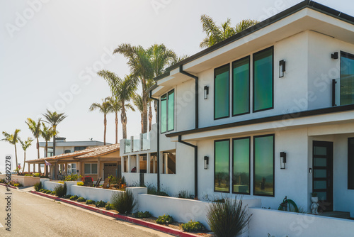 Modern beachfront homes with large windows and palm trees under a clear sky.