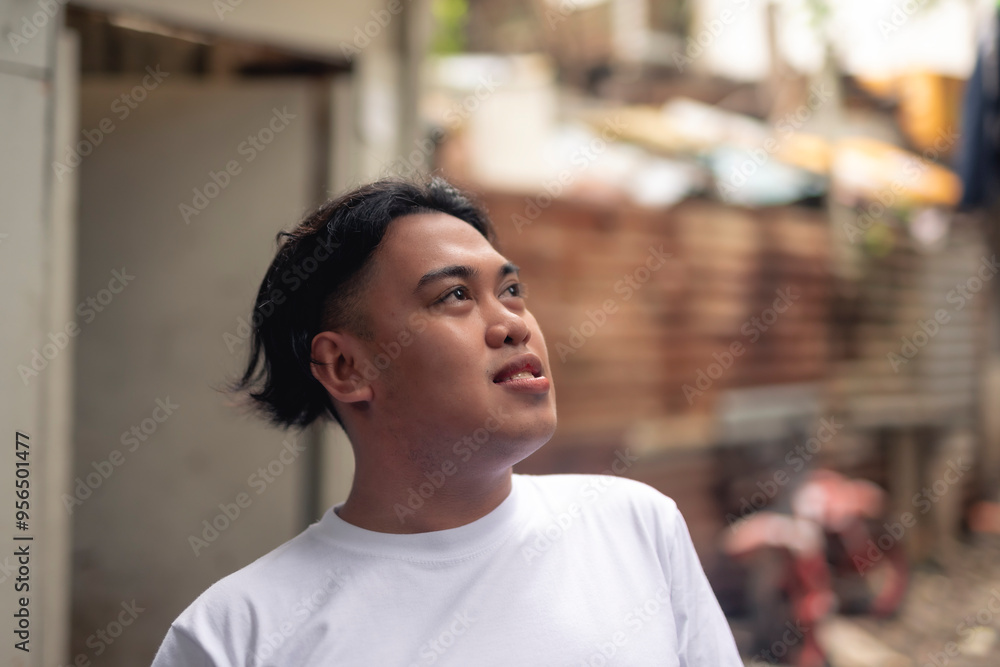 An optimistic man looking up while in front of a slum area. A young Filipino residing in an squatter area. Shantytown background. An optimistic man looking up while in front of a slum area. A young Filipino residing in an squatter area. Shantytown background.