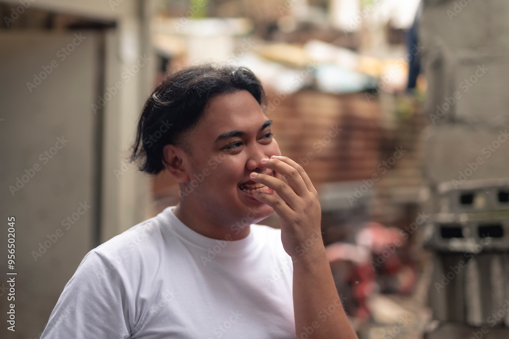 Candid portrait of a LBGT person giggling. A young Filipino residing in an squatter area. Shantytown background. Candid portrait of a LBGT person giggling. A young Filipino residing in an squatter area. Shantytown background.