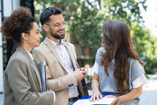 Three diverse business people working and talking focused and thoughtful seriously outside office building, male and female, discussing plans and work project. Businessman and businesswoman teamwork.