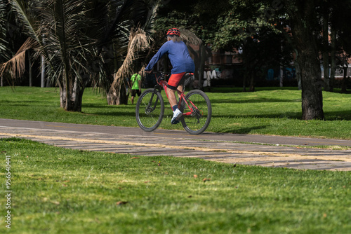 Man on a sports bike on the bike path cycling in the park on a sunny day