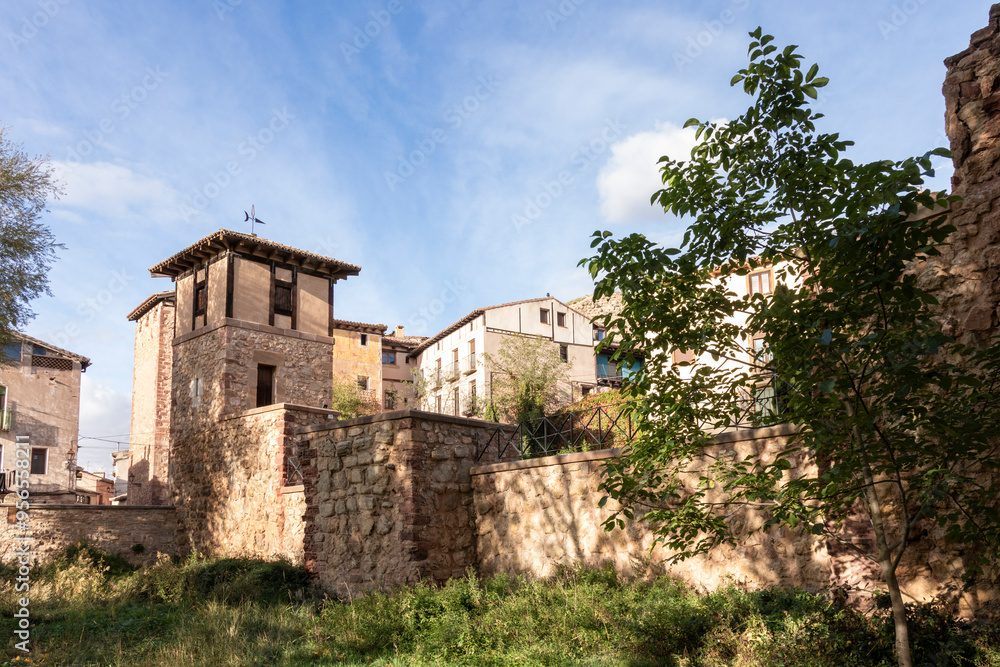 A small village with a few houses and a tree. The houses are old and the sky is blue A small village with a few houses and a tree. The houses are old and the sky is blue