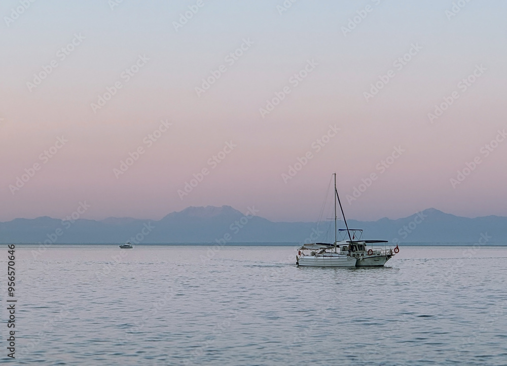 Evening seascape. White yacht sailing in the sea against the backdrop of sunset and mountains. Evening seascape. White yacht sailing in the sea against the backdrop of sunset and mountains.