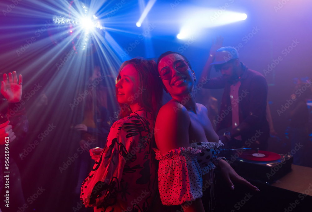 Fototapeta premium People dancing and jumping at disco. Evening enjoyment in music club. Nightlife, modern music and entertainment concept