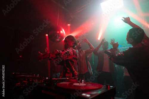 Photos Beautiful Dj woman mixing songs on control panel and crowd dancing in the backgr