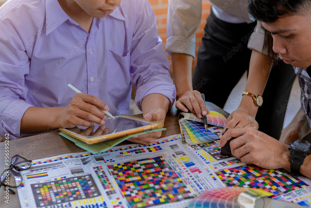 Team graphic designer checking print quality of media graphics proof print and color guides in printing industry. Selected focus Team graphic designer checking print quality of media graphics proof print and color guides in printing industry. Selected focus