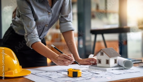 Mujer trabajando en un proyecto de arquitectura en un estudio con un plano, un metro y una maqueta