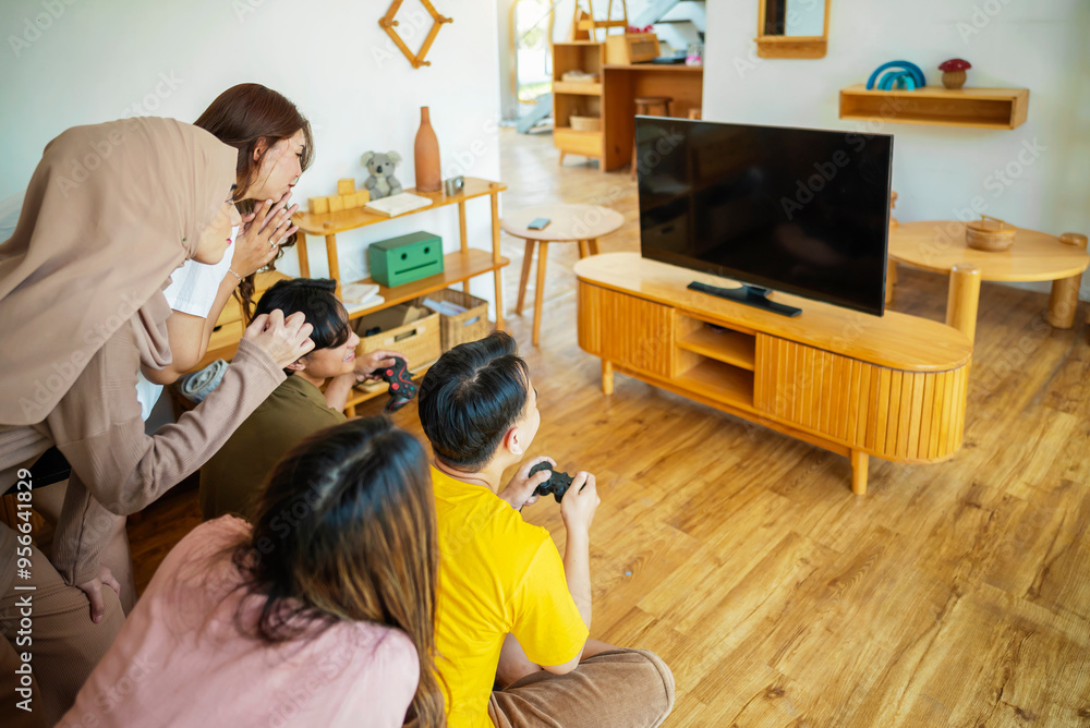 An Indonesian group of people are playing video games in a living room An Indonesian group of people are playing video games in a living room