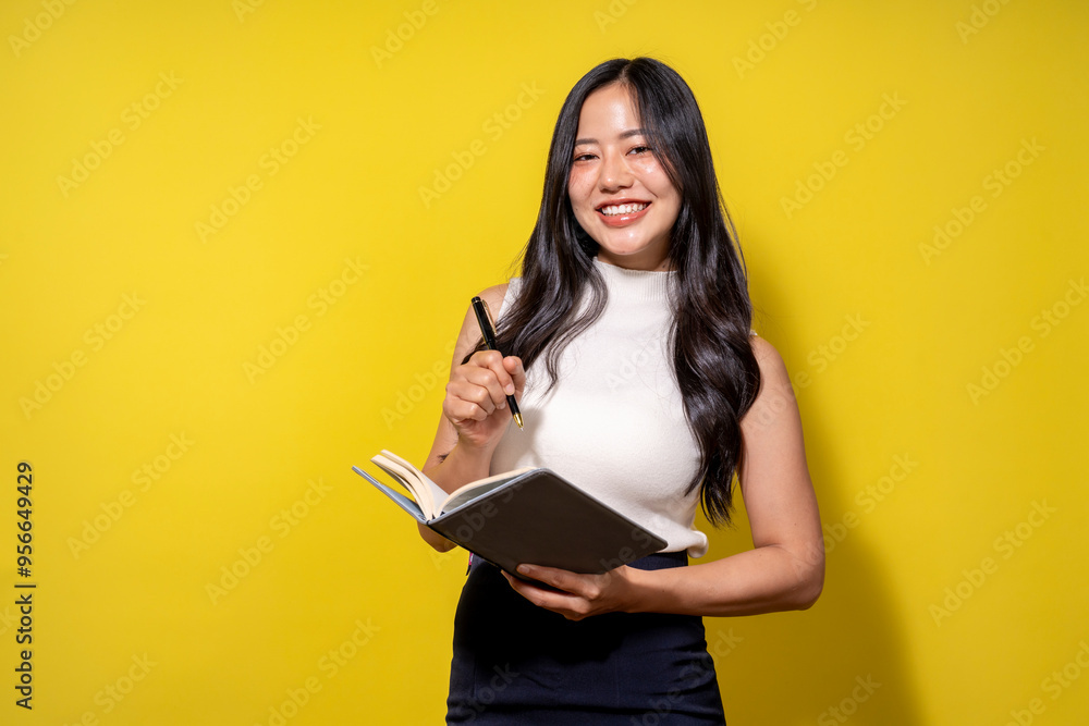 A woman is holding a book and a pen, smiling A woman is holding a book and a pen, smiling
