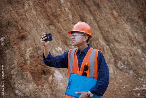 young male construction worker taking pictures at his work site for a report to his boss