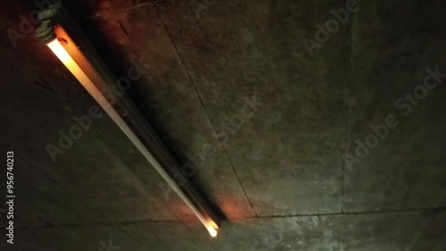 Flickering neon tube in garage with scary malfunction and dysfunction of neon lights flickers glowing and alarming or threatening in halloween atmosphere dramatic darkness gaslight with error switch