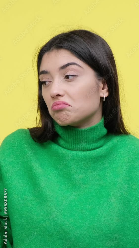 Puzzled and uncertain young adult Caucasian woman spreading arms on yellow background. Concept of a dilemma and doubt. Vertical video. Puzzled and uncertain young adult Caucasian woman spreading arms on yellow background. Concept of a dilemma and doubt. Vertical video.
