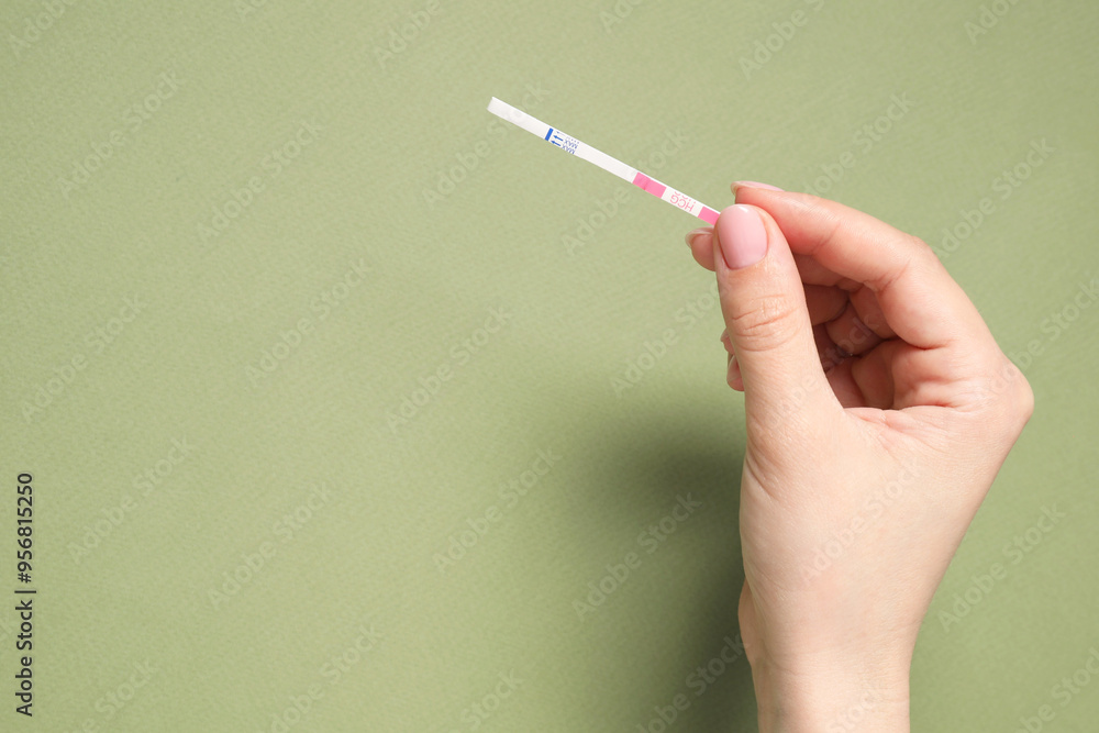 Woman holding pregnancy test on olive background, top view. Space for text Woman holding pregnancy test on olive background, top view. Space for text