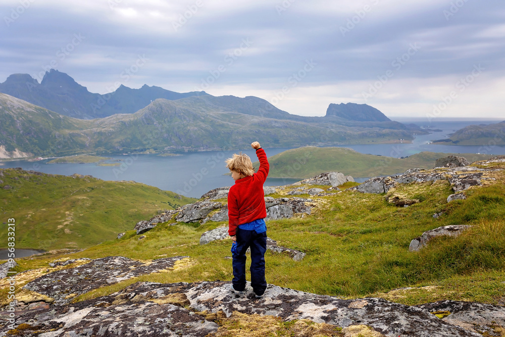 Happy children with parents and dog, european family, hiking the Kvalvika trail on hill at Kvalvika beach, Norway