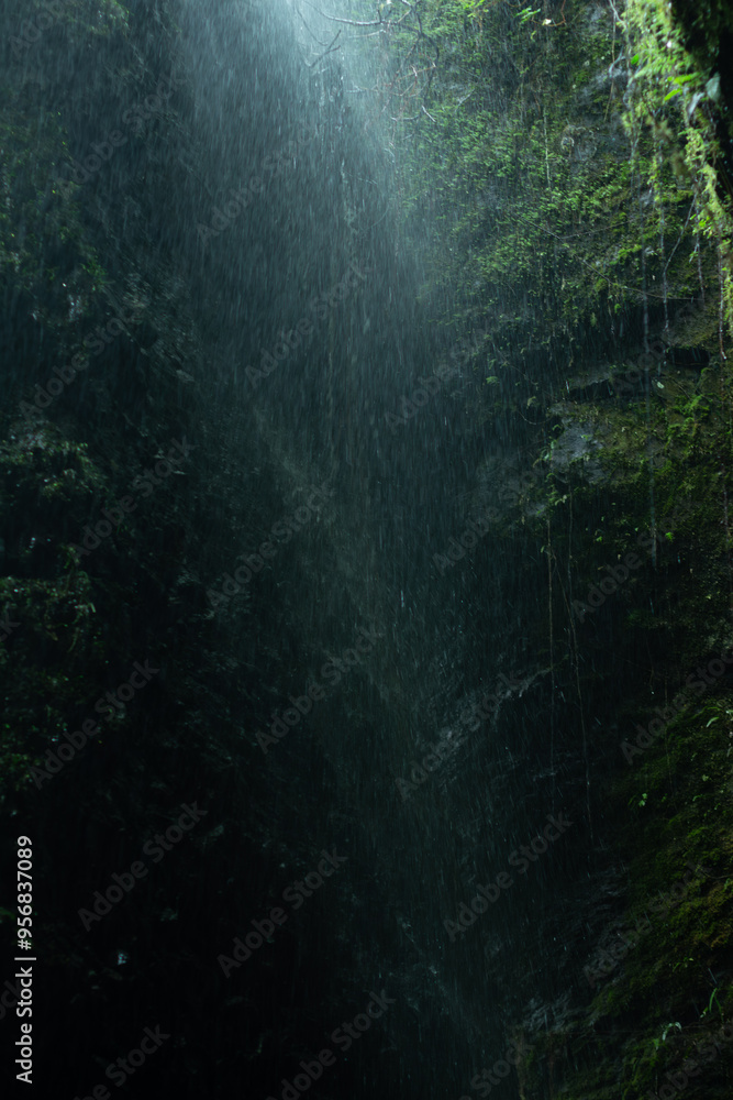 Obraz premium Creative and artistic composition in the Cueva del Esplendor, cave of splendor, Jardin, Jardín, Antioquia, Colombia. Dark abstraction with rain falling on a rock and droplets in a ray of light.