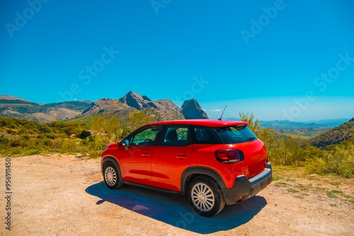 Red car stopped on dirt road in mountains of Andalucia
