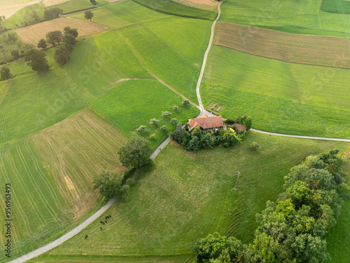 Aerial view of farm house in rural area in Switzerland. Road through fields.