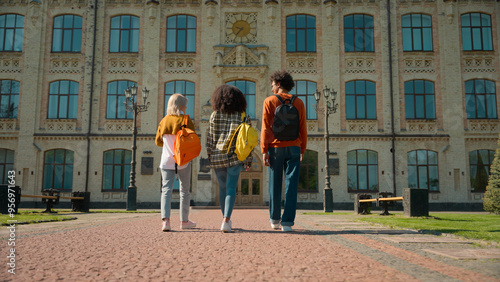 Back view three multiracial people outside go to class lesson studying together students diversity friends man guy male Caucasian African females women girls walking outdoor school university college