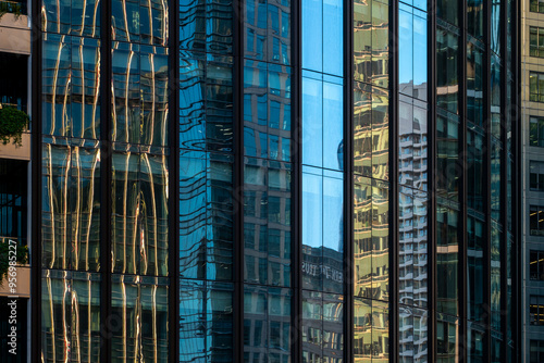 Abstract reflections of assorted urban architecture on colorful glass windows, presenting a kaleidoscopic view of the city's dynamic and modern landscape amid light play.