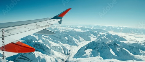 Aerial view from an airplane wing over snow-covered mountain ranges, showcasing a breathtaking frozen landscape below.