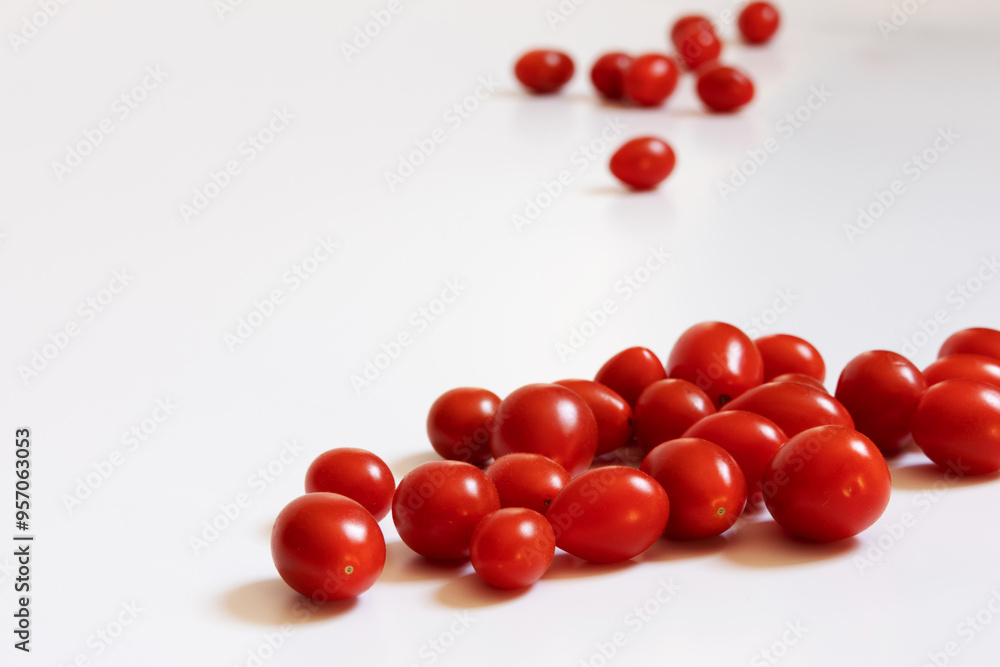 Portion of ripe cherry tomatoes in the foreground and another portion in the background out of focus, all on a white background Portion of ripe cherry tomatoes in the foreground and another portion in the background out of focus, all on a white background