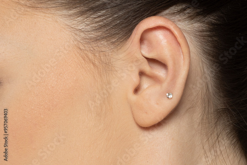 Closeup of female ear with one gemstone earring photo