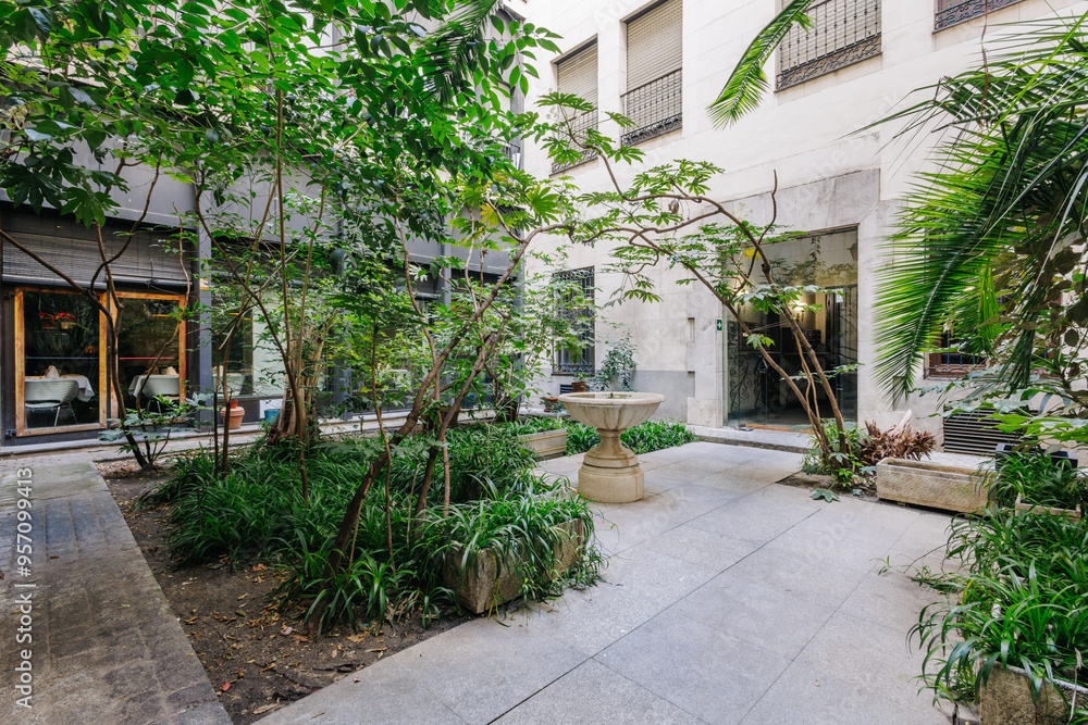 A serene courtyard features lush, green plants and trees A serene courtyard features lush, green plants and trees