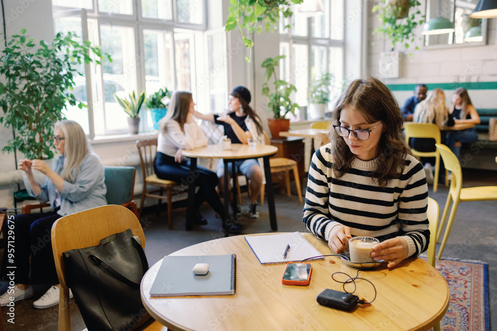 Young female student drinking coffee and doing homework in cafe Young female student drinking coffee and doing homework in cafe