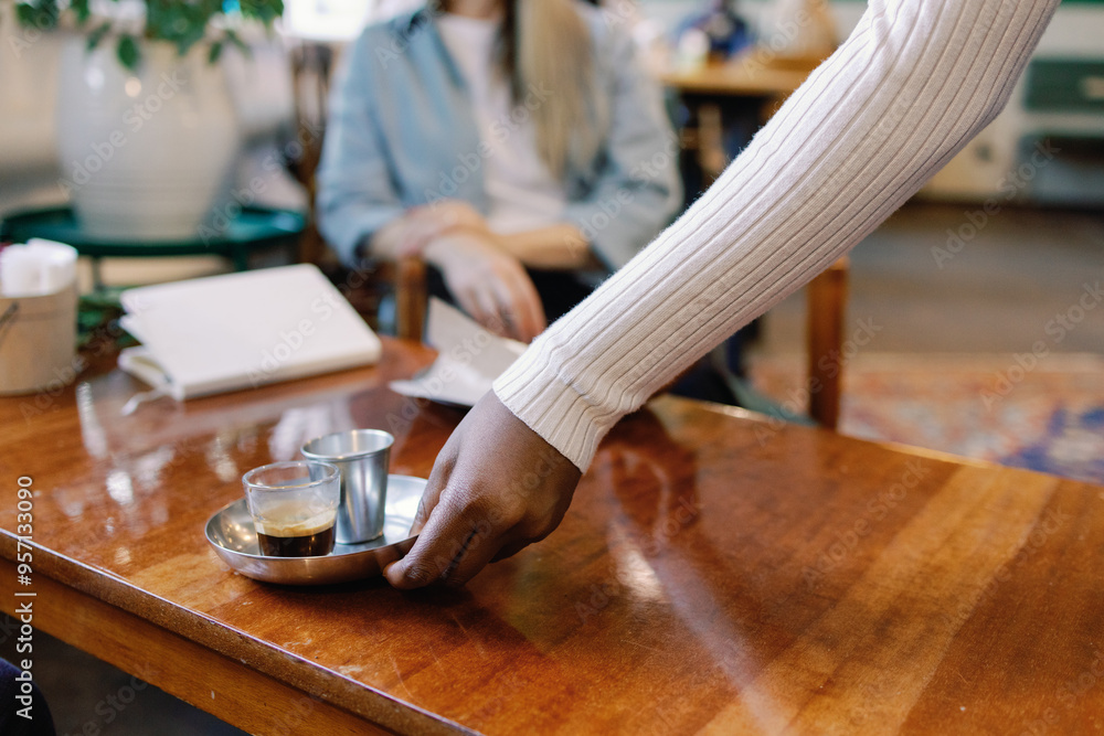 Cropped of black waitress putting on order on table to client in cafe Cropped of black waitress putting on order on table to client in cafe