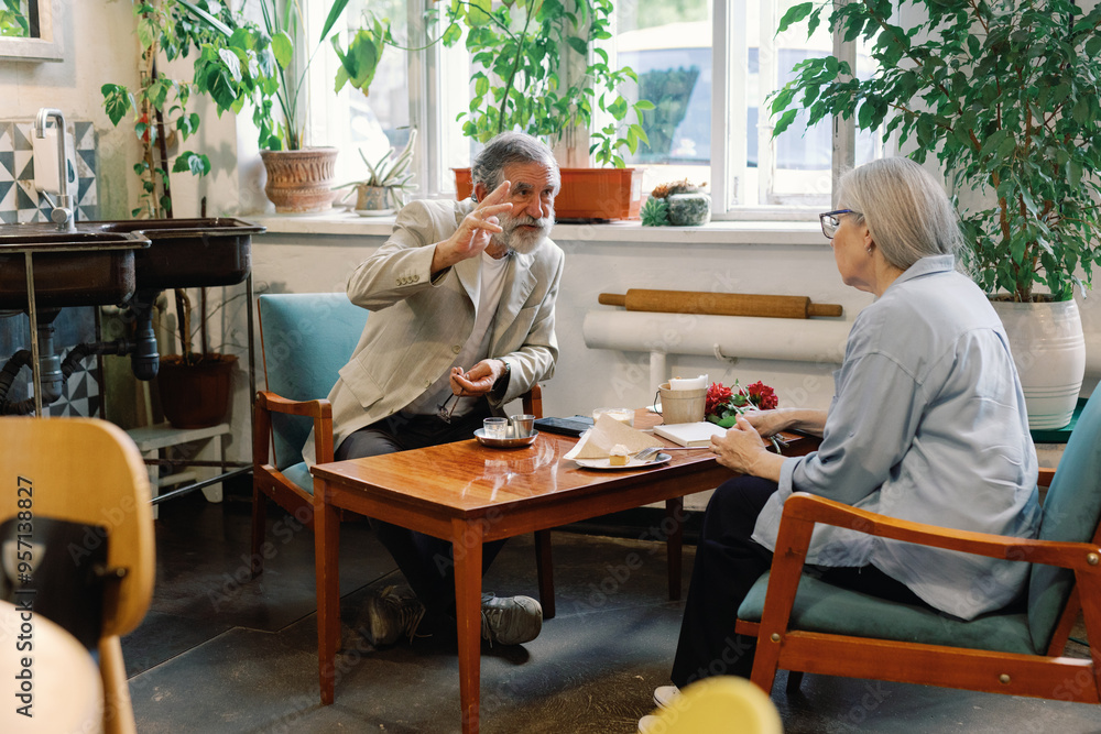 Man telling something to woman at table in modern cafe at daytime Man telling something to woman at table in modern cafe at daytime