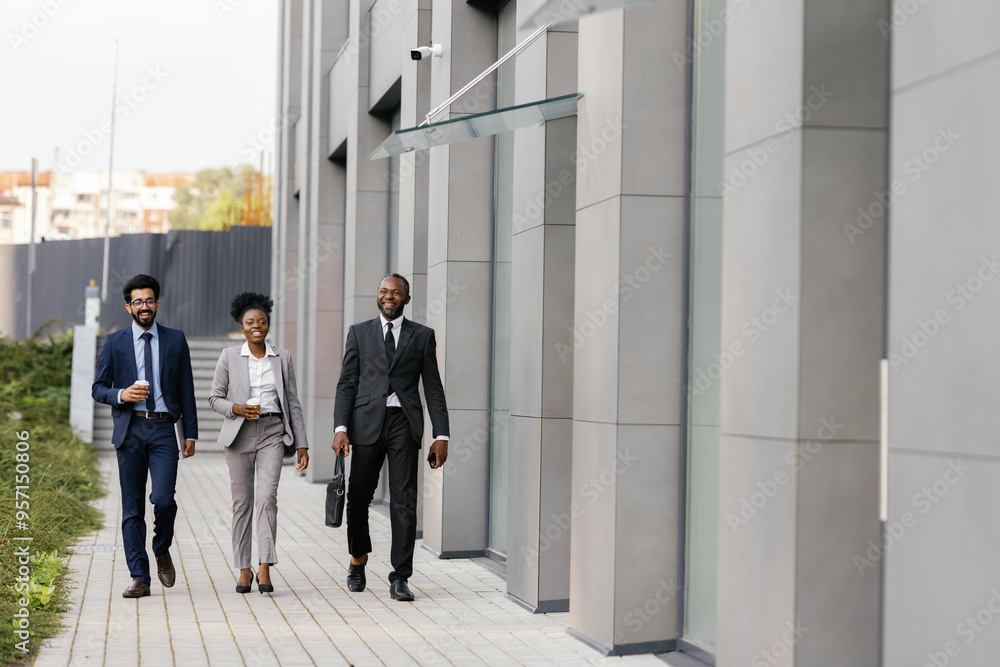 Joyful businesspeople strolling past facade of office building Joyful businesspeople strolling past facade of office building
