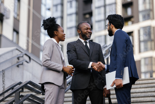 Office manager shaking hands with business partner outdoors