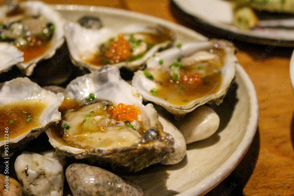 Fresh oysters sit on top of rocks, garnished with roe, soy sauce, and fresh chives, ready to be slurpled. Fresh oysters sit on top of rocks, garnished with roe, soy sauce, and fresh chives, ready to be slurpled.