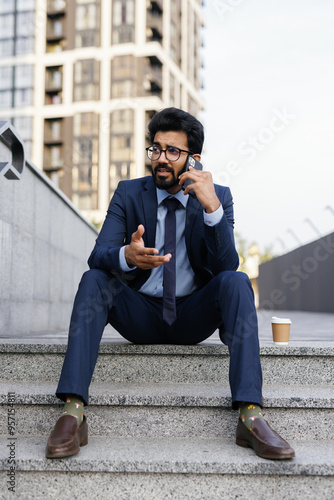 Displeased businessman talking on mobile phone outside photo