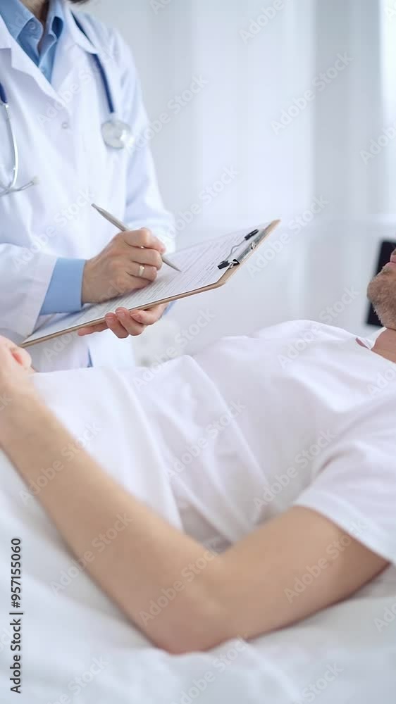 Female doctor writing medical report of patient lying in bed in hospital Female doctor writing medical report of patient lying in bed in hospital