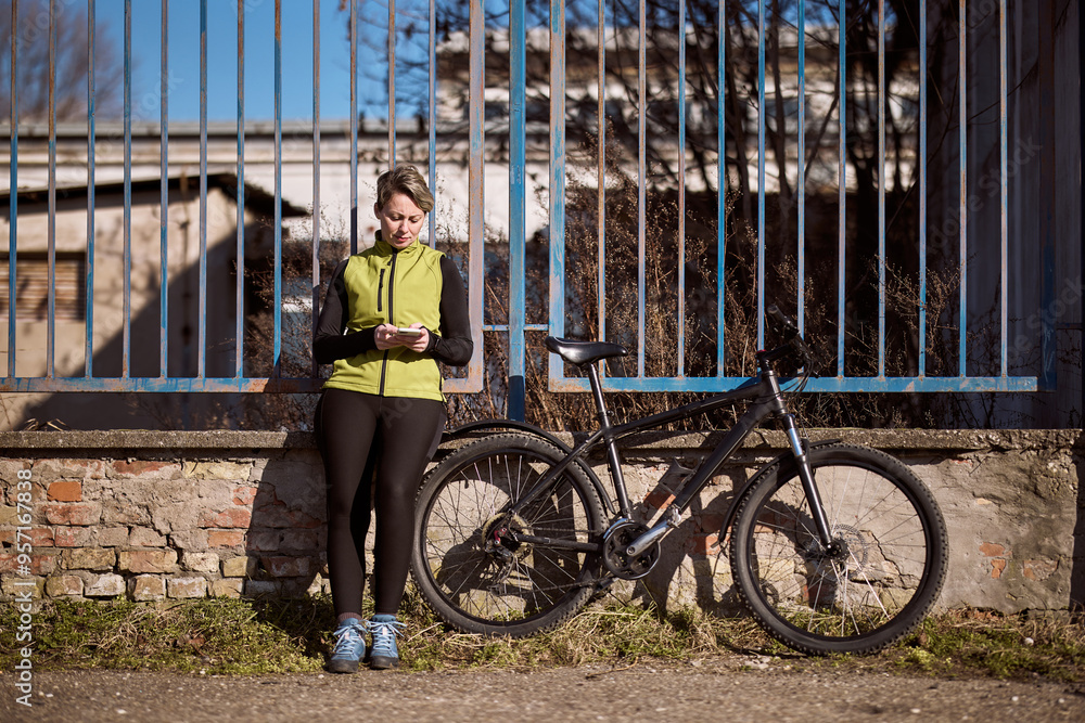 Obraz premium Woman Next to Bike Texting on Phone