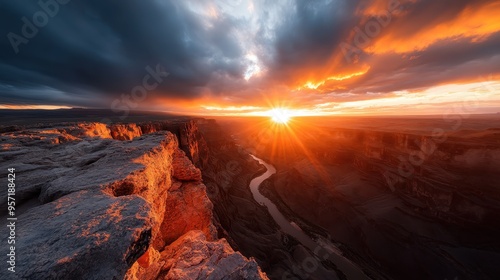 An awe-inspiring sunrise over a vast, breathtaking canyon with a river winding gracefully through it, emphasized by dramatic clouds and vibrant colors in the sky. photo