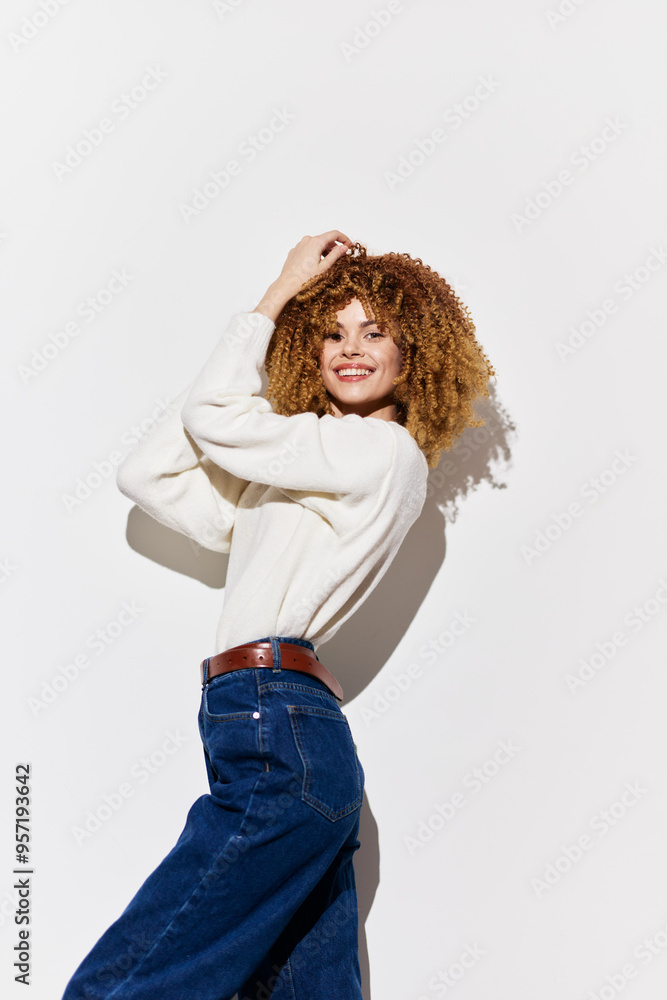 Smiling woman in a white sweater and blue jeans against a light background, showcasing natural curls and a joyful expression, perfect for fashion and lifestyle themes Smiling woman in a white sweater and blue jeans against a light background, showcasing natural curls and a joyful expression, perfect for fashion and lifestyle themes