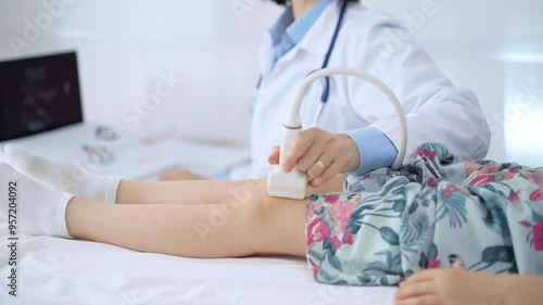 Doctor and kid patient. Orthopedist performing ultrasound examination on a child's knee in a clinic. Medicine and health care photo